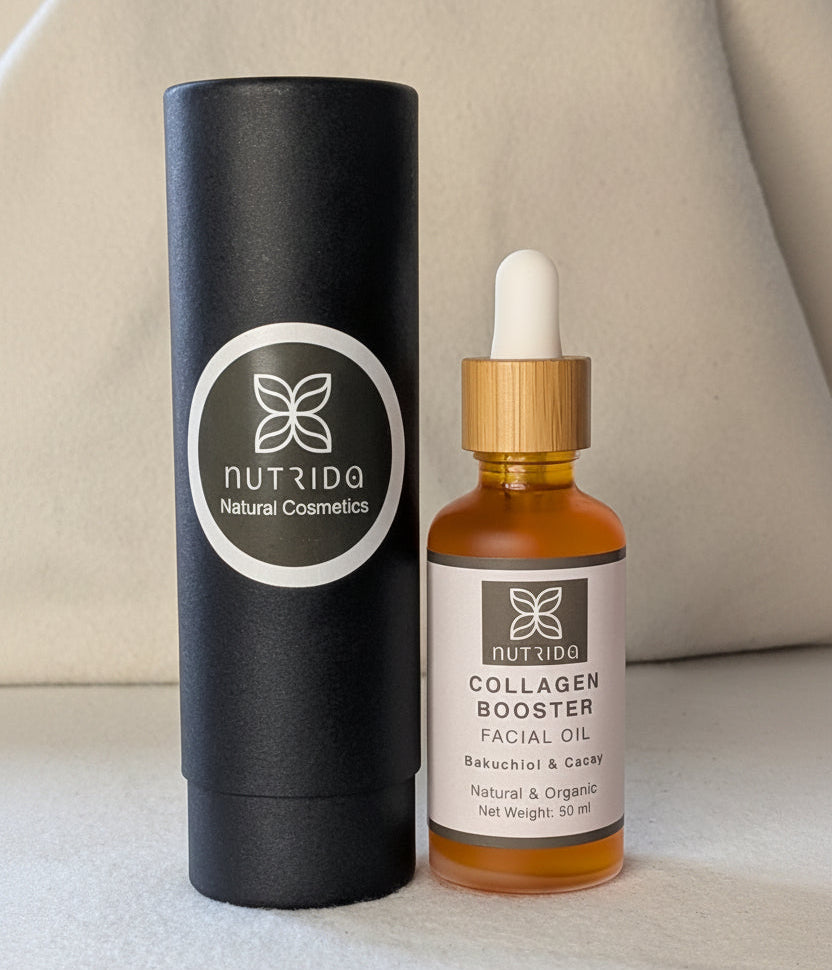 A bottle of Nutrida Collagen Booster facial oil with a white dropper cap and amber glass, standing next to its tall black cylindrical packaging tube on a light fabric surface.