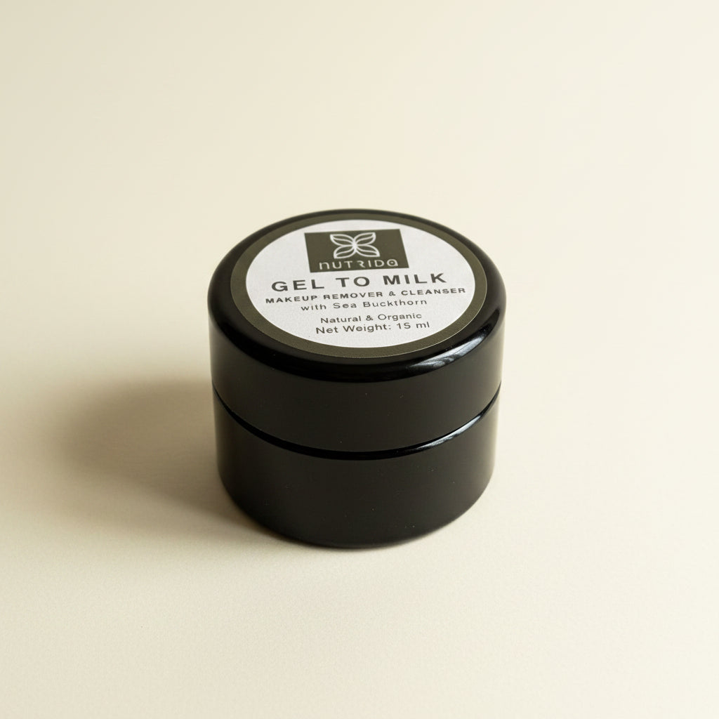 A small black plastic jar of Ruzido Gel to Milk Makeup Remover & Cleanser, resting on a textured white fabric background.