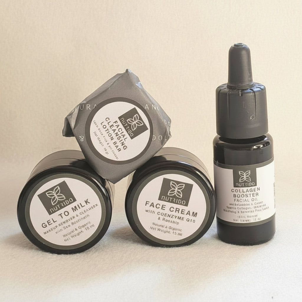 Three skincare products from the brand 'The Beauty Bar' arranged on a light beige background: two round black jars of Gelatin Milk and Face Cream, and one black dropper bottle of Tallow Face Oil.