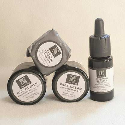 Three skincare products from the brand 'The Beauty Bar' arranged on a light beige background: two round black jars of Gelatin Milk and Face Cream, and one black dropper bottle of Tallow Face Oil.