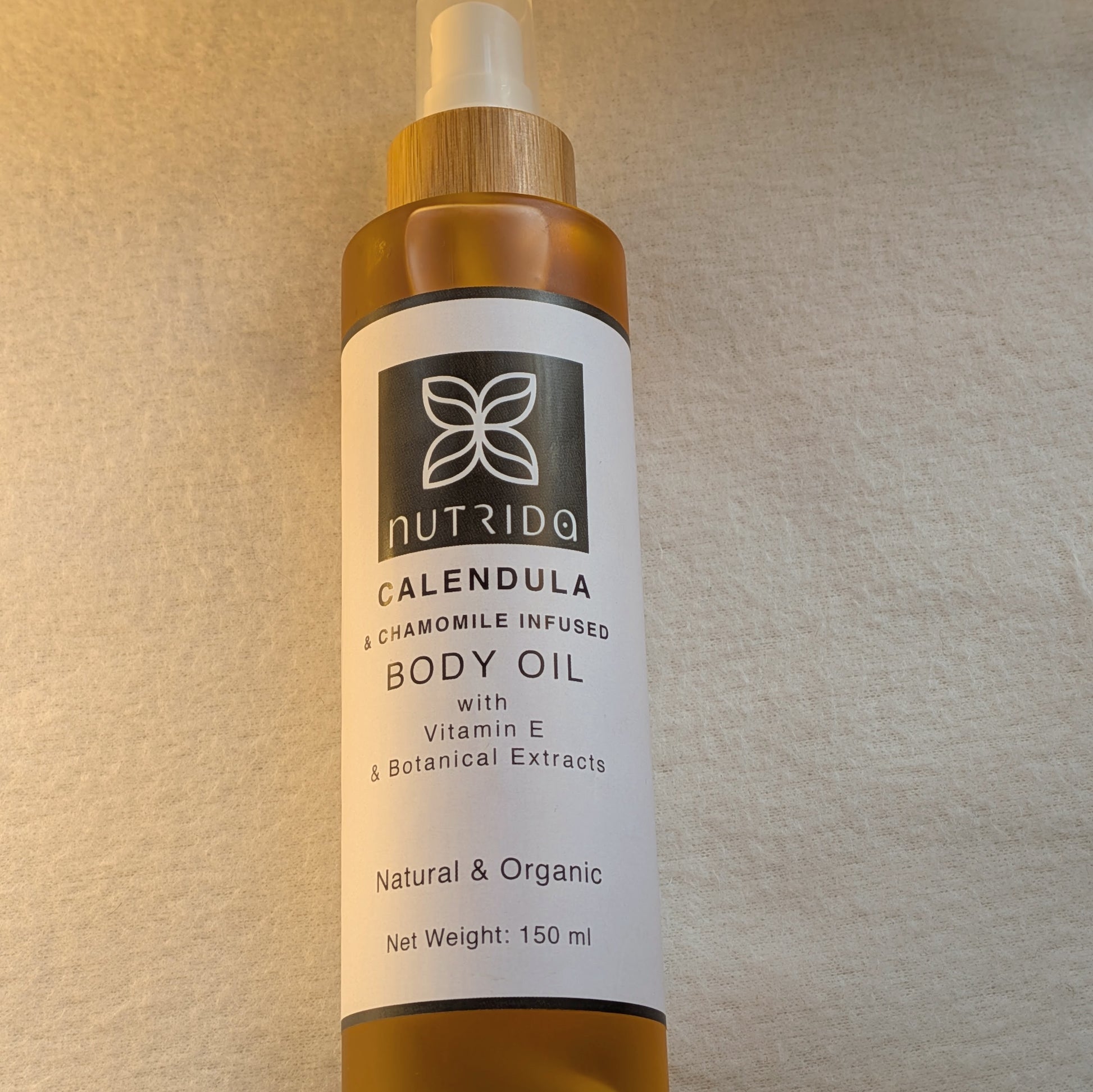Bottle of Nutrida Calendula body oil on a beige background