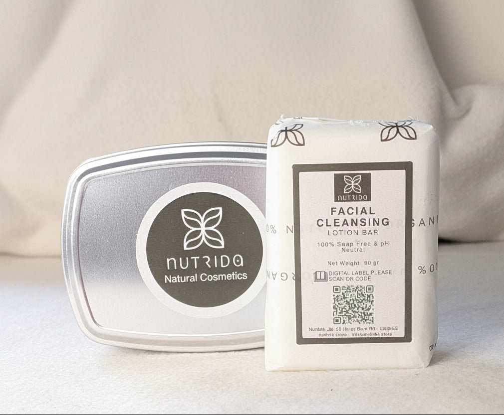 A packaged facial cleansing lotion bar standing upright next to its silver tin container on a soft beige fabric surface. The front label reads 'NUTRIDQA Natural Cosmetics' and 'FACIAL CLEANSING LOTION BAR'.