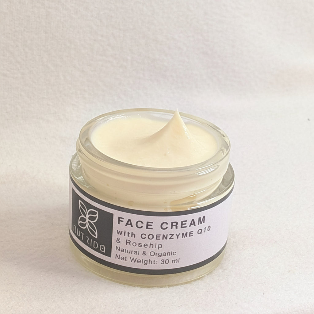 A 30 ml clear glass jar of NutriDQ Face Cream with a white label and black text, showing a swirl of pale cream inside, set against a textured off-white background.