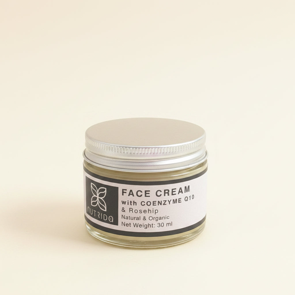 A 30 ml jar of Nutridg Face Cream with Coenzyme Q10 and Rosehip, featuring a silver metal lid and a white label with black text, set against a soft, textured off-white background.
