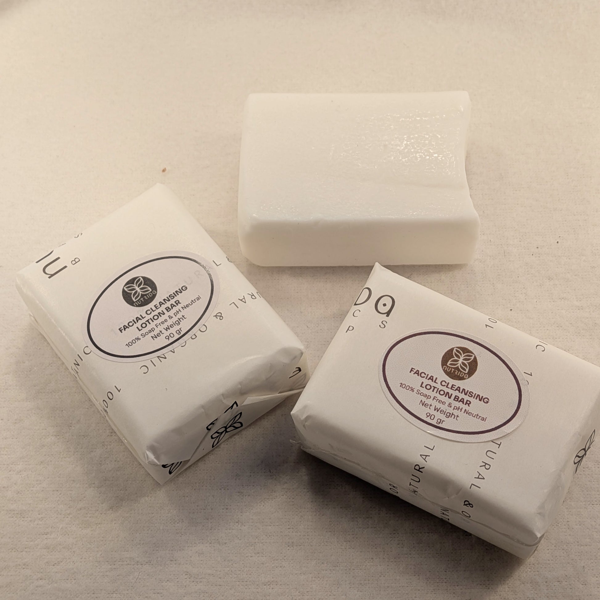 Three facial cleansing lotion bars on a beige surface with visible branding.